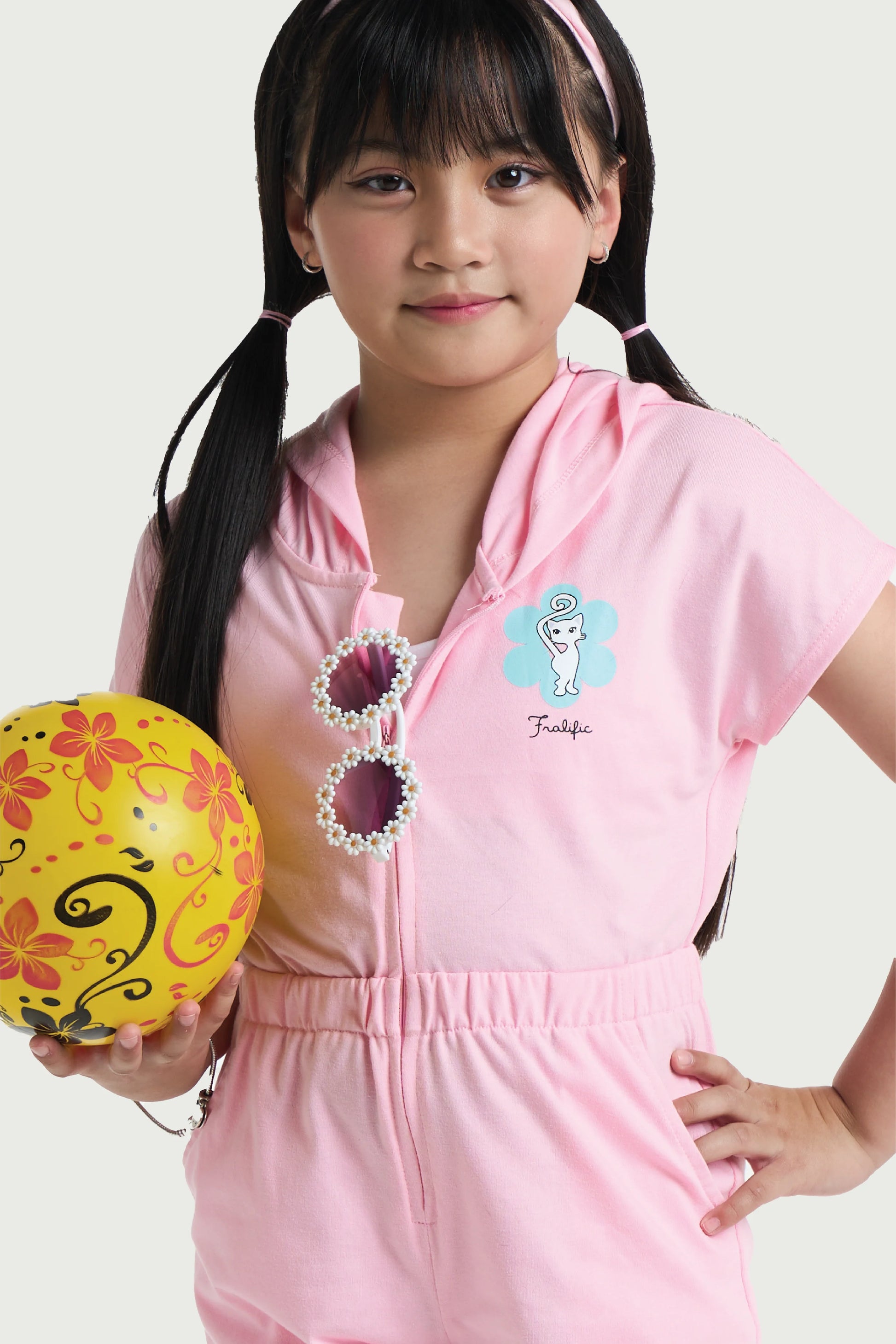 Little girl playing in pink romper for summer with hood and short sleeves